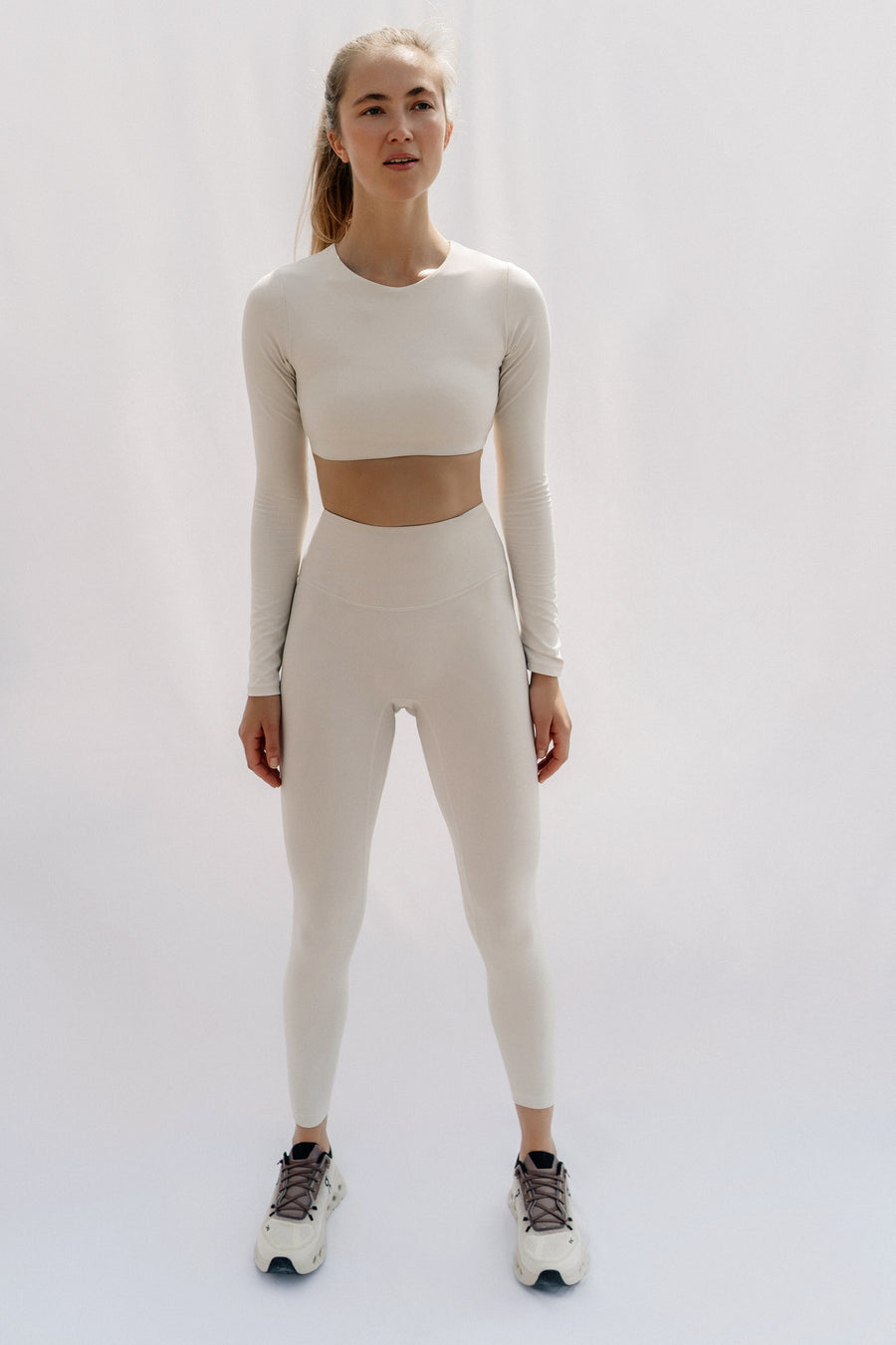 Woman wearing a beige athletic outfit on a white background
