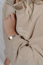 Beige sweatshirt with a brand logo on a plain background