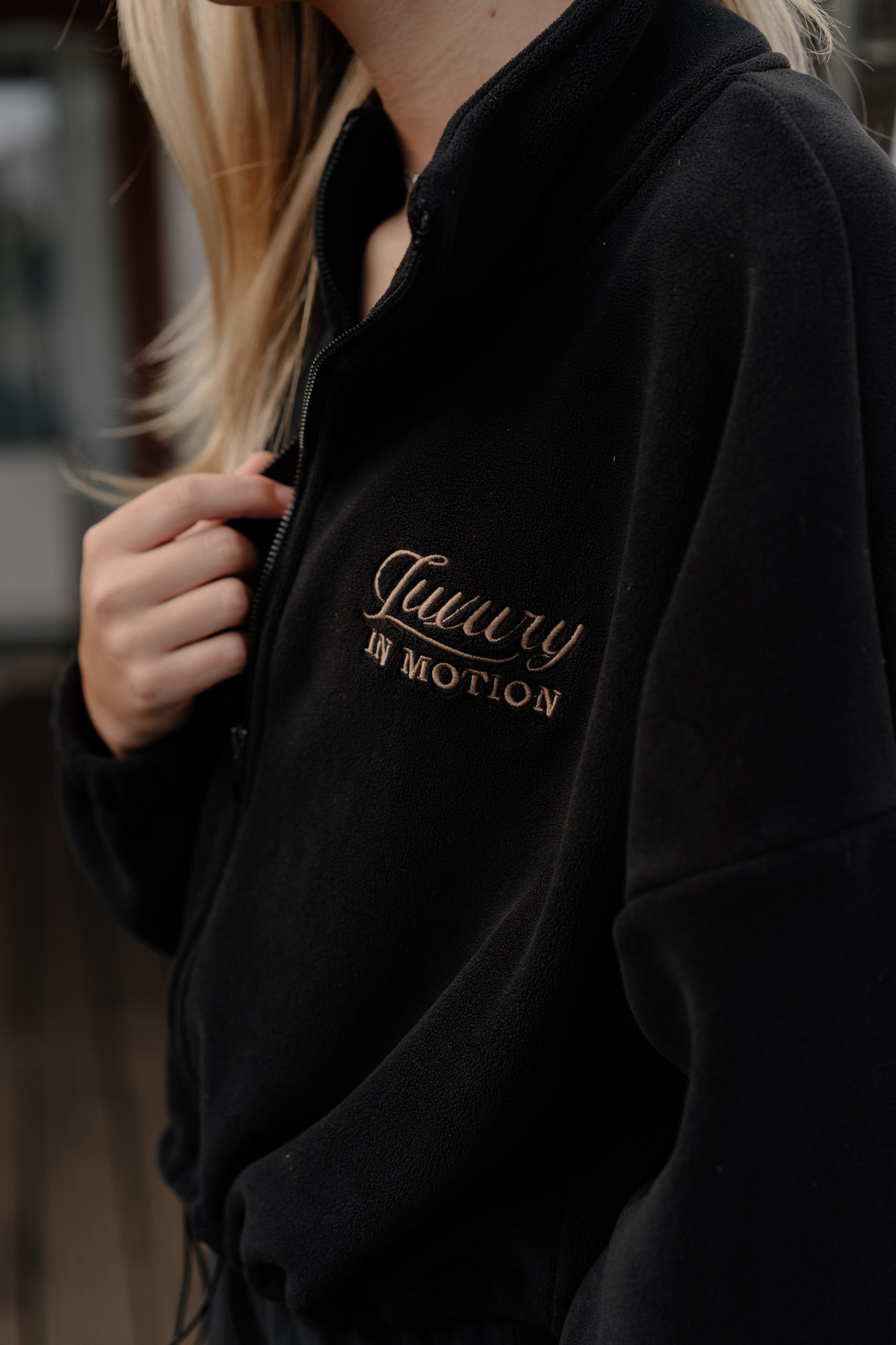 Black hoodie with 'Luxury in Motion' text on a blurred background