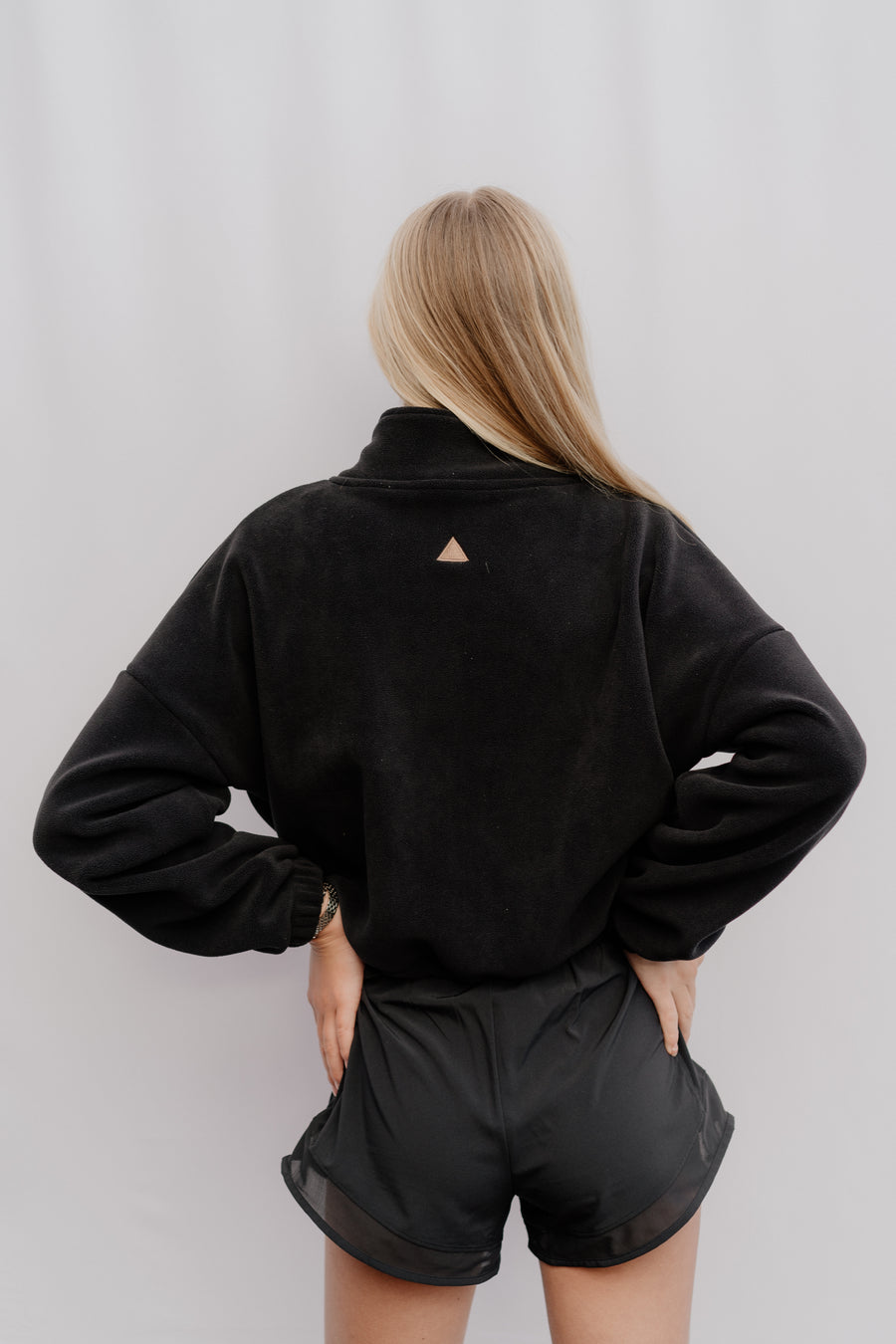 Woman wearing a black jacket and shorts against a plain background