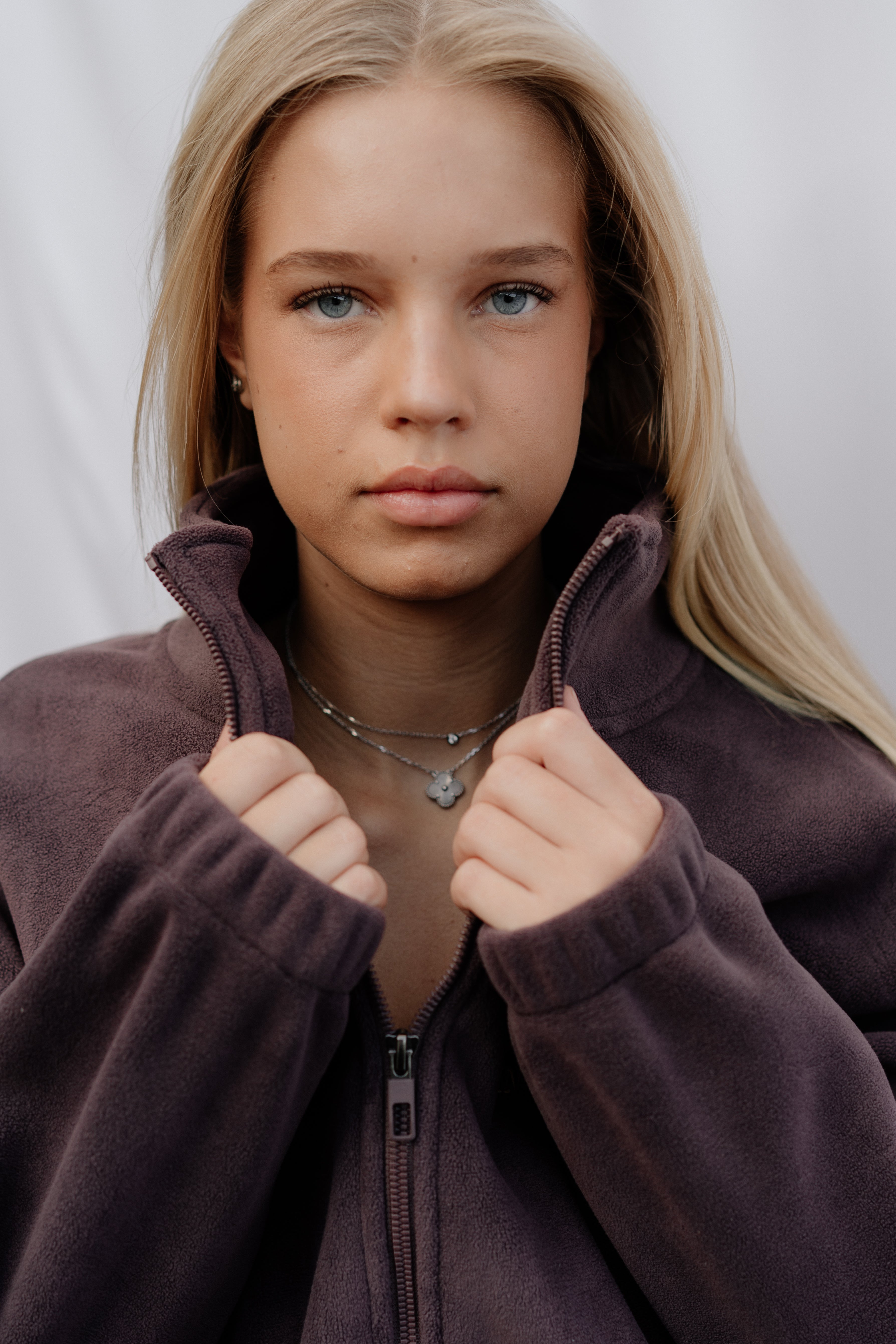 Woman wearing a brown zip-up hoodie against a plain background