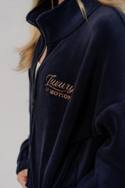 Navy blue jacket with 'Luxury in Motion' text on a plain background