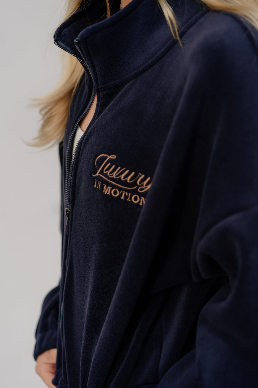 Navy blue jacket with 'Luxury in Motion' text on a plain background