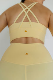 Yellow sports bra and leggings set with criss-cross straps on a plain background