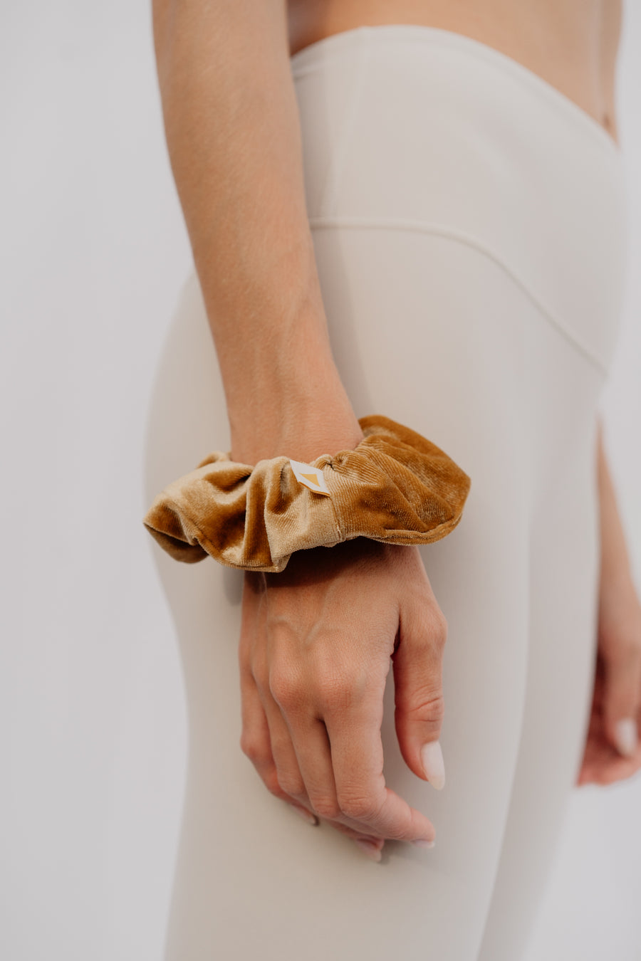 Woman wearing a gold scrunchie on a plain background