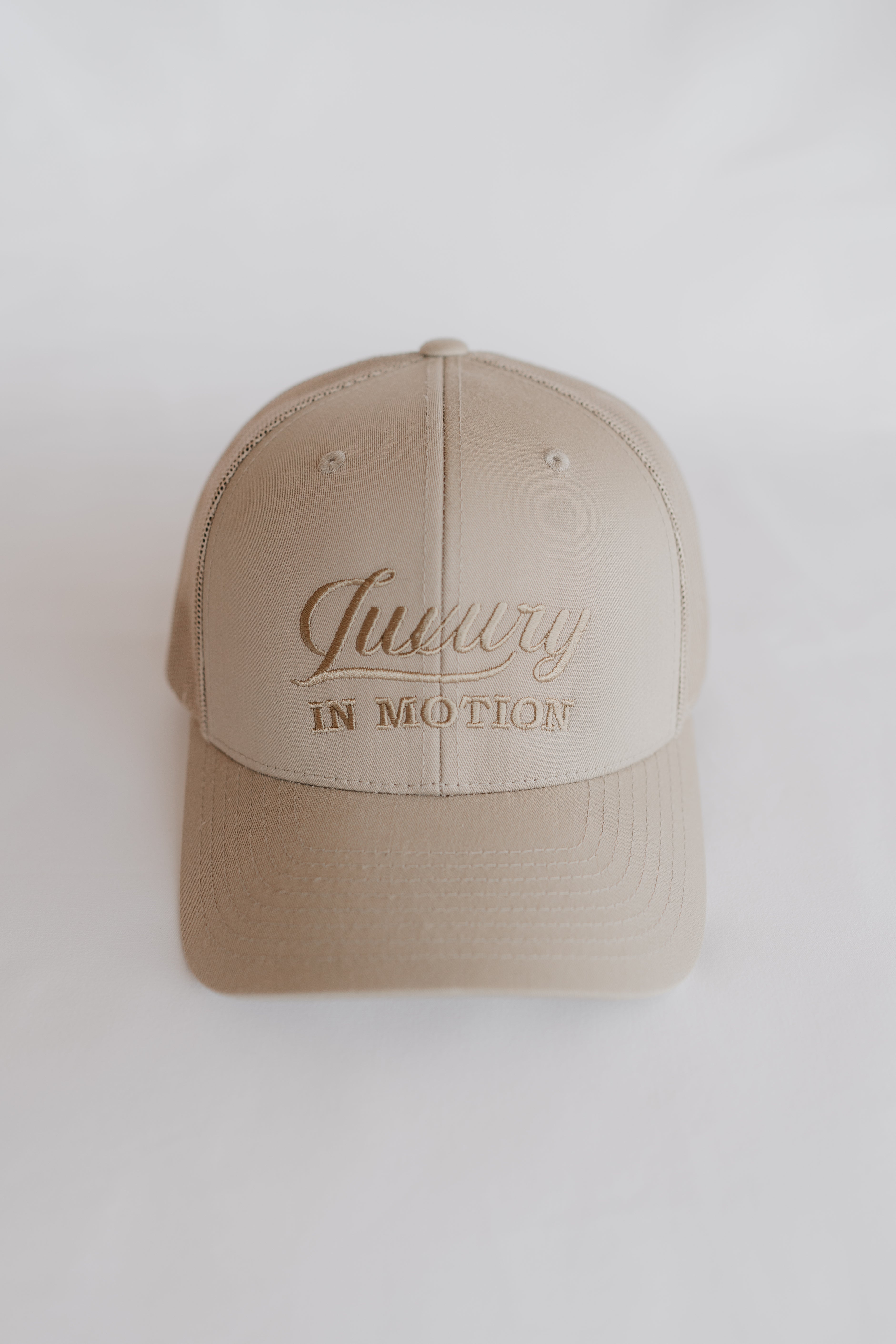 Beige cap with 'Luxury in Motion' text on a white background