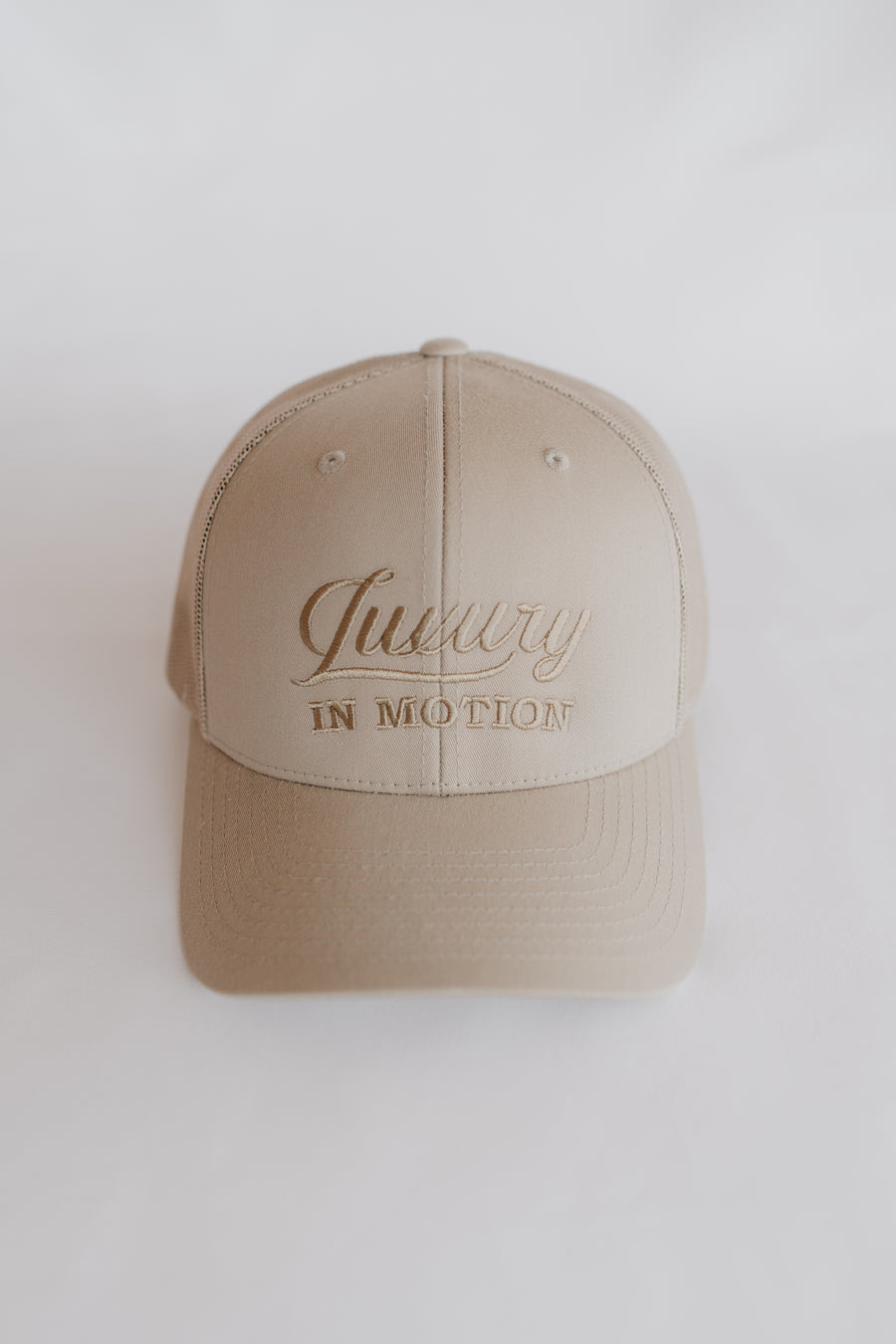 Beige cap with 'Luxury in Motion' text on a white background