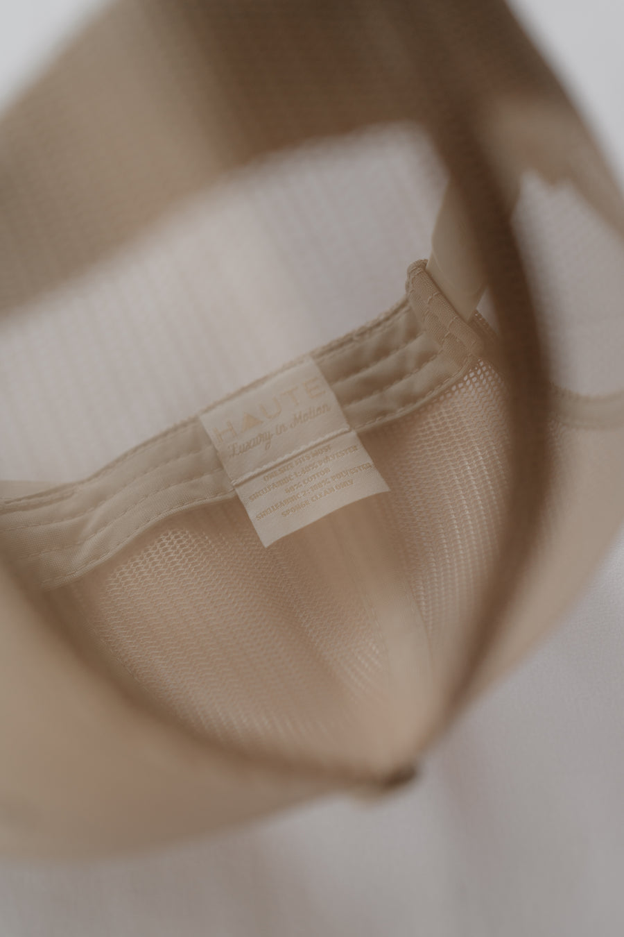 Close-up of a beige woven bag with a strap on a neutral background