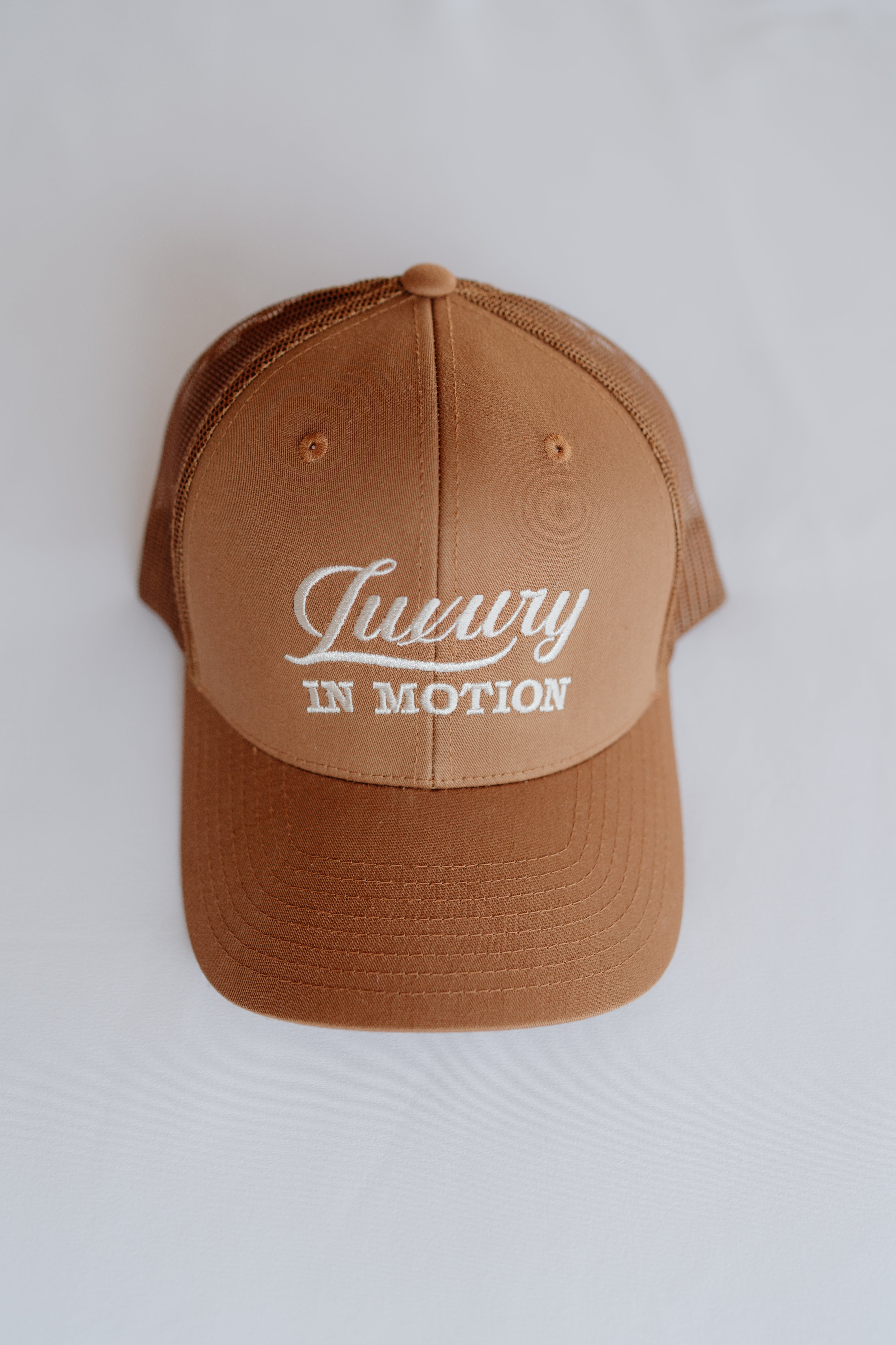 Brown cap with 'Luxury in Motion' text on a white background