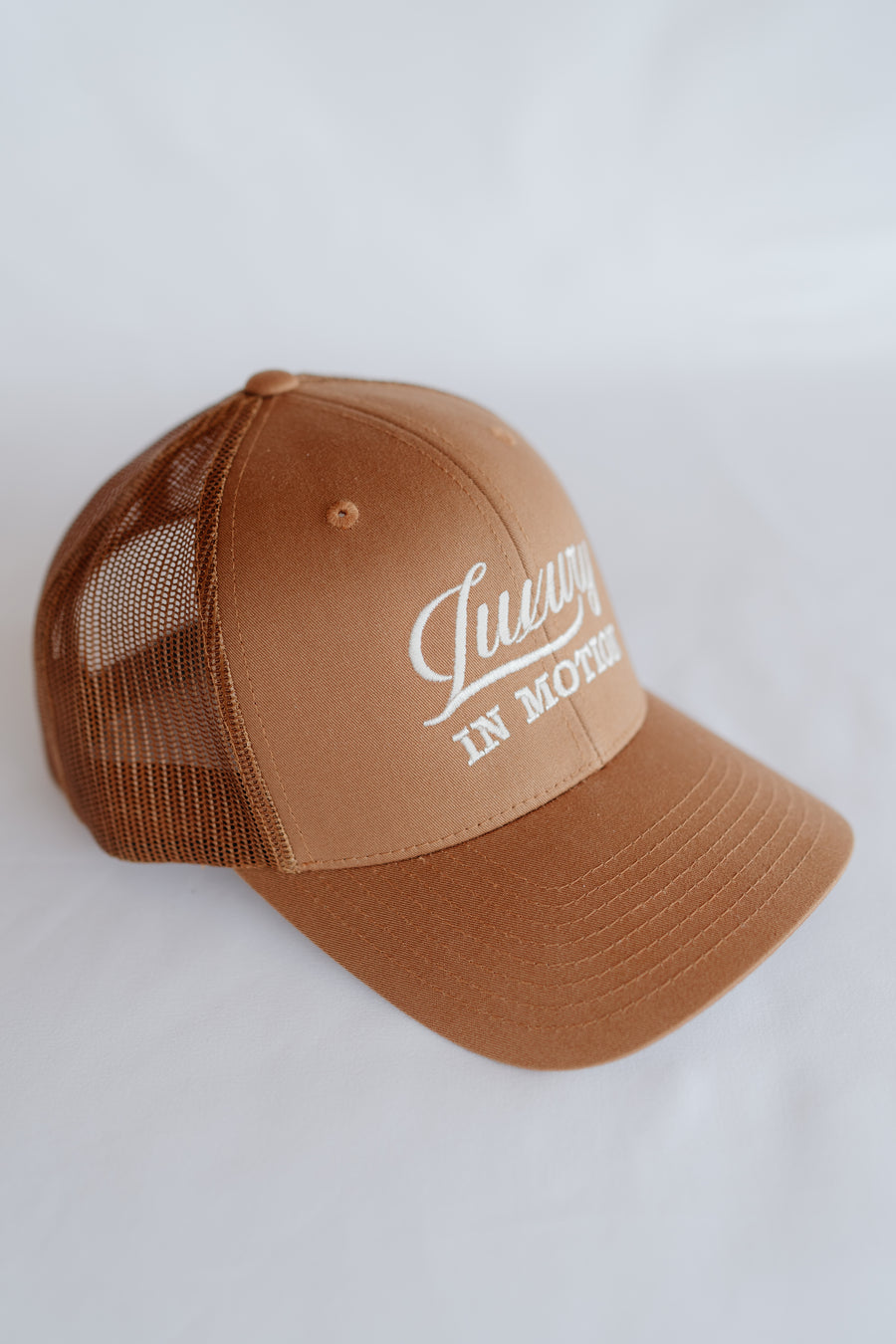 Brown cap with mesh back and white text on a white background