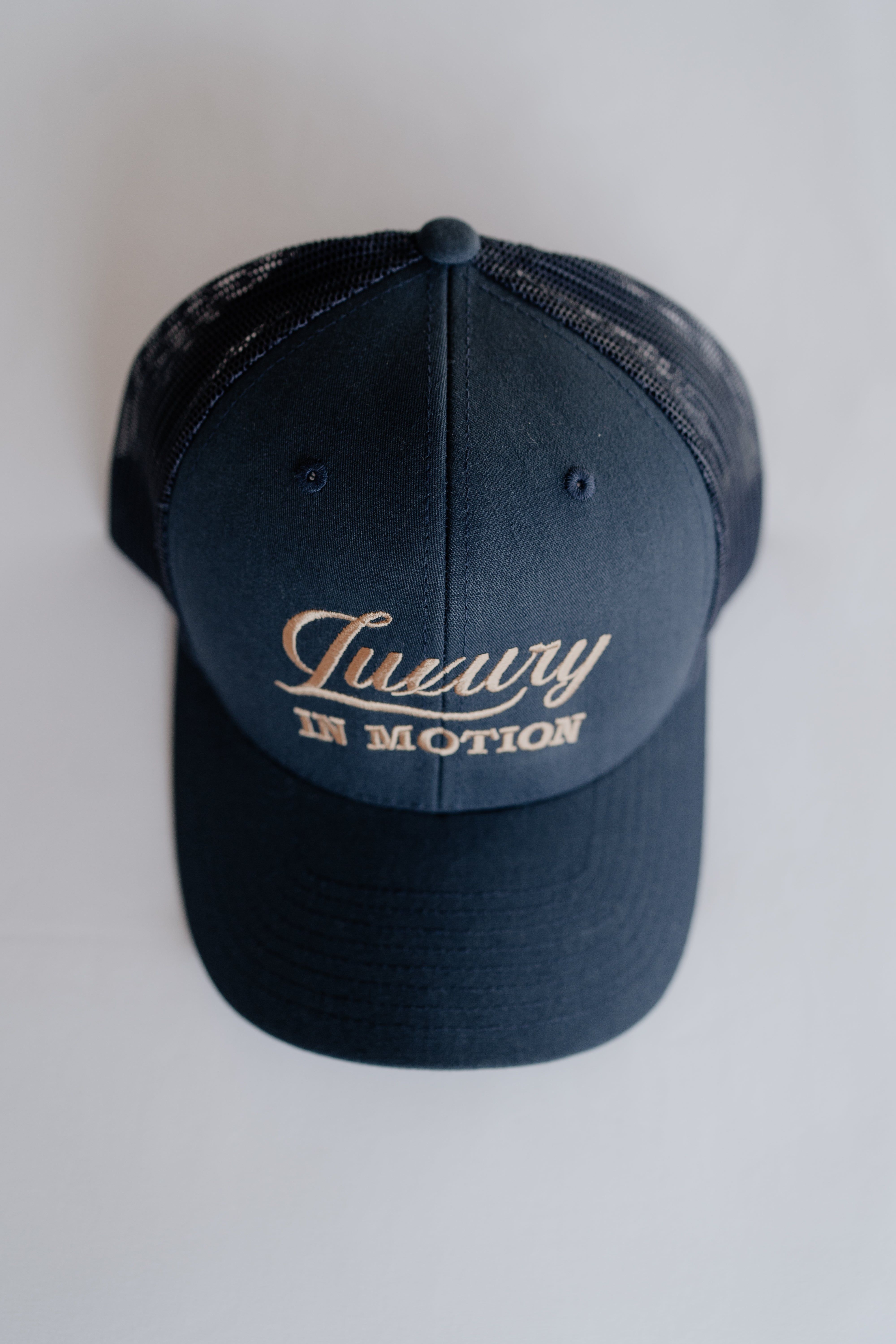 Navy blue cap with 'Luxury in Motion' text on a white background