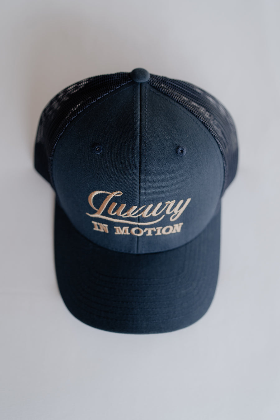 Navy blue cap with 'Luxury in Motion' text on a white background