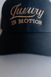 Navy blue cap with 'Luxury IN MOTION' embroidery on a neutral background