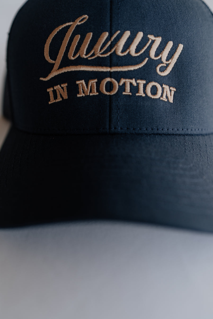 Navy blue cap with 'Luxury IN MOTION' embroidery on a neutral background
