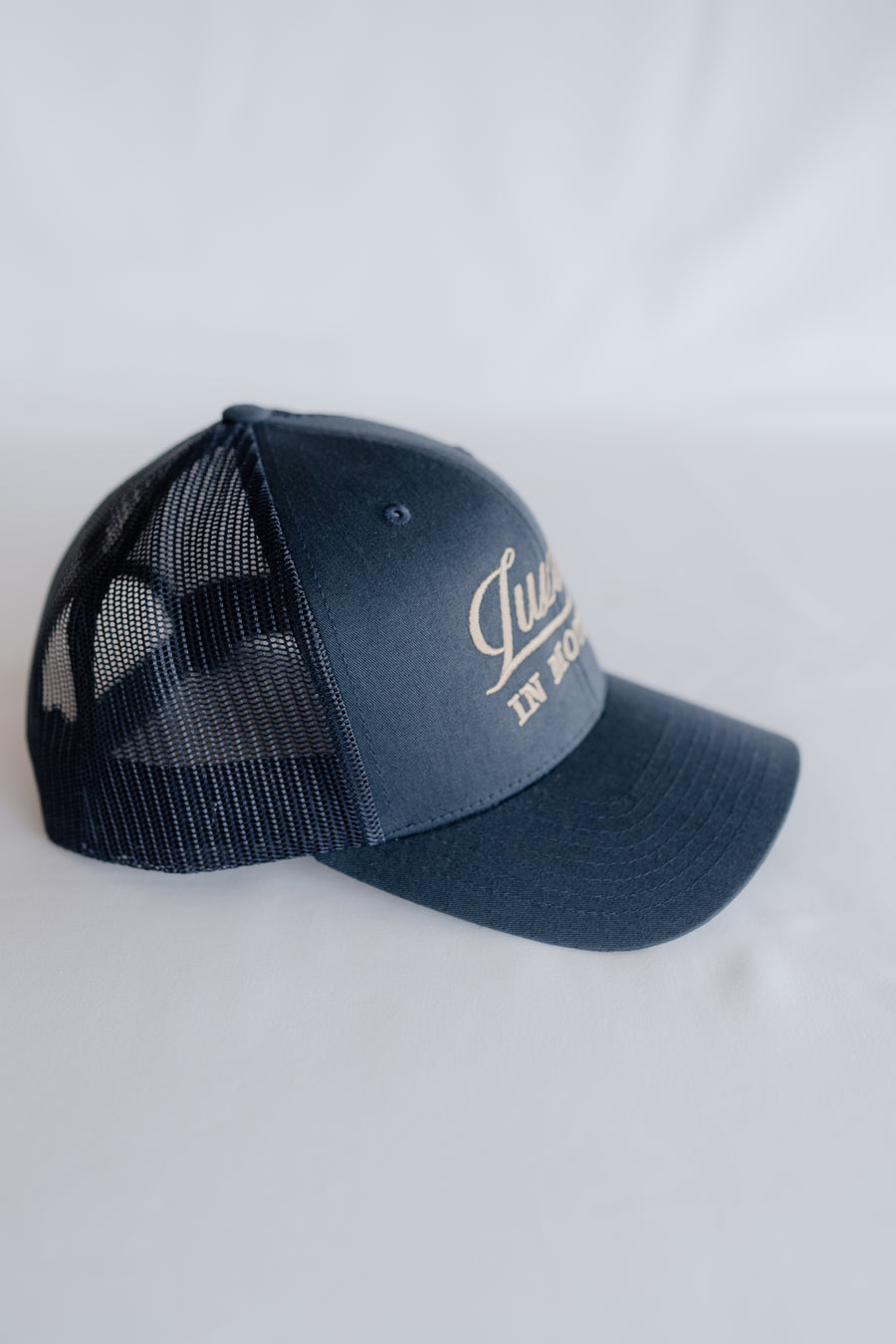 Navy blue cap with mesh back and white text on a white background