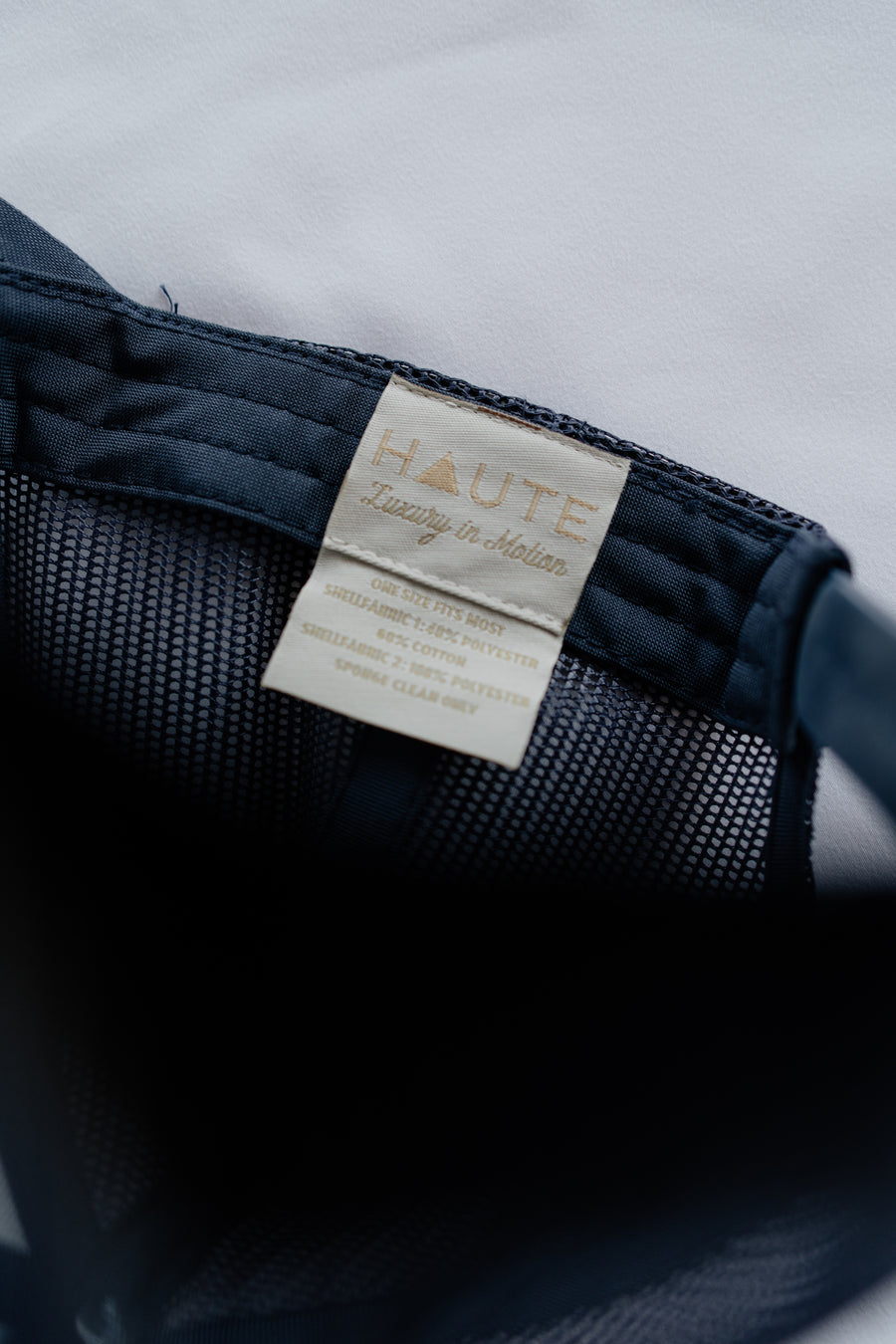 Close-up of a navy blue garment with a 'HAUTE' label on a light gray background