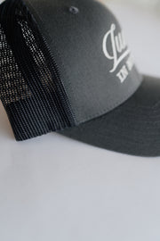 Grey cap with mesh back and white logo on a light gray background