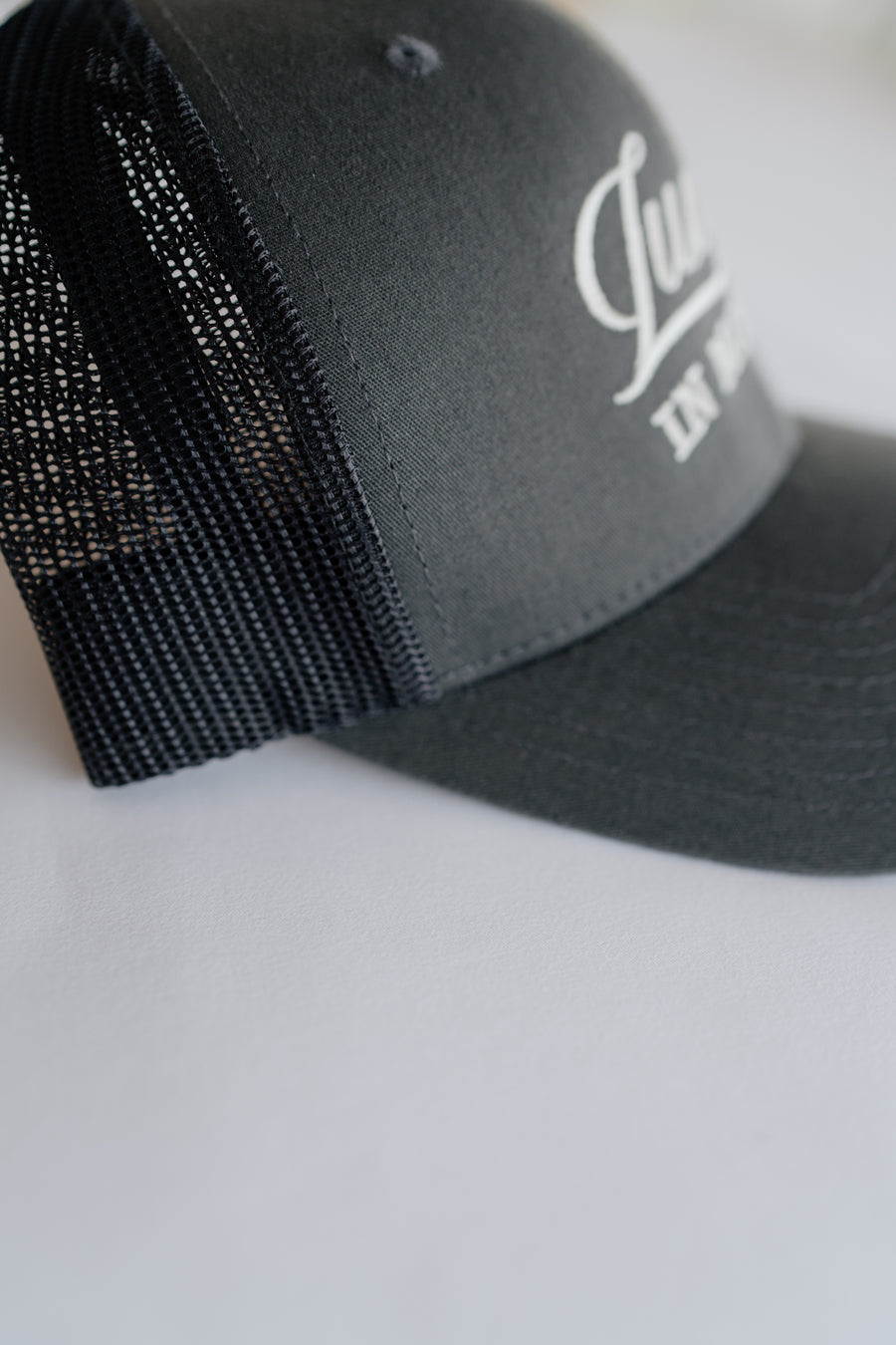 Grey cap with mesh back and white logo on a light gray background