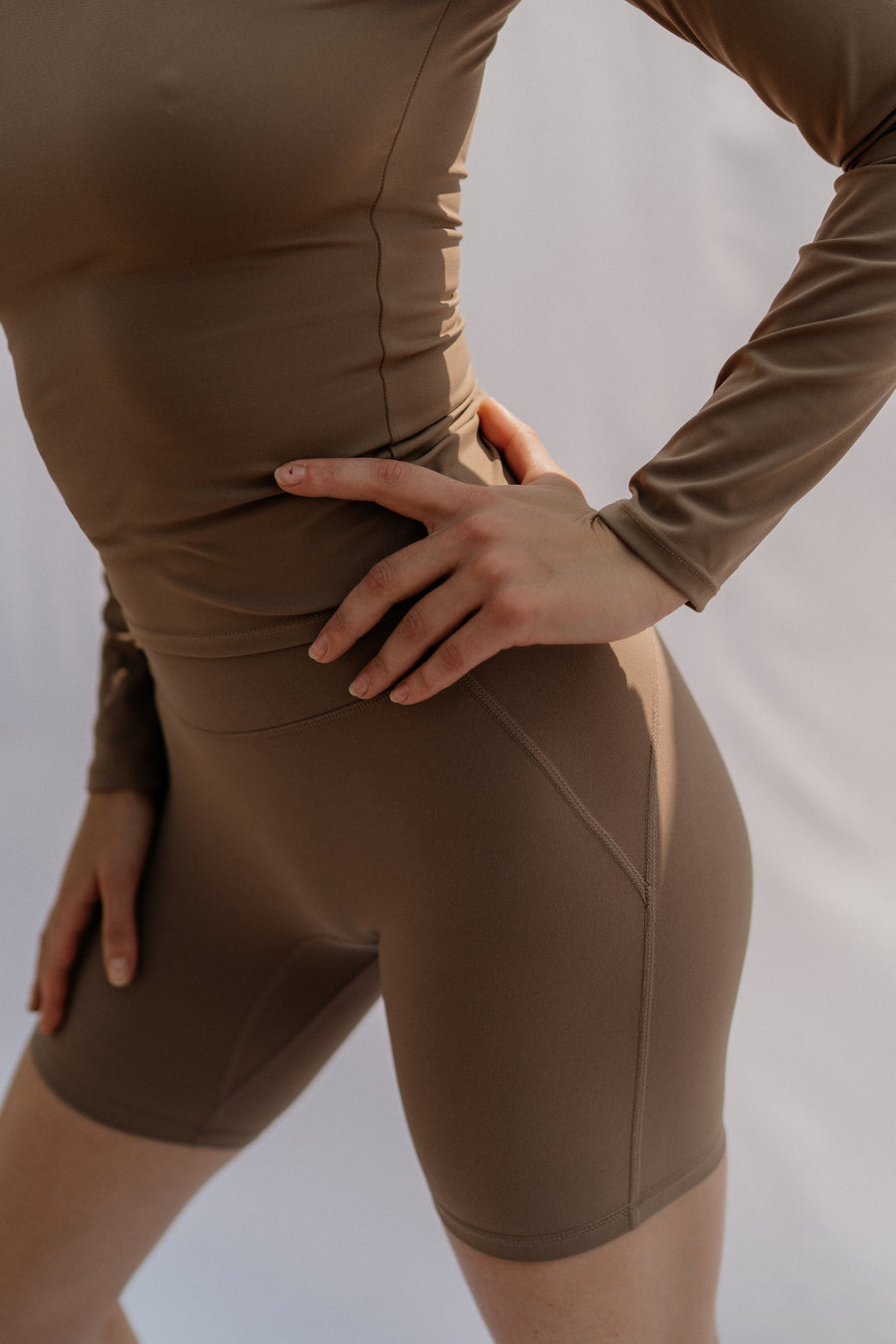 Woman wearing a brown athletic outfit on a plain background