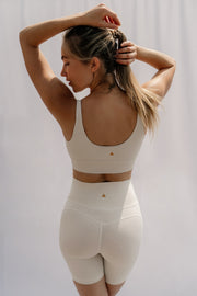 Woman wearing a beige athletic outfit against a white background