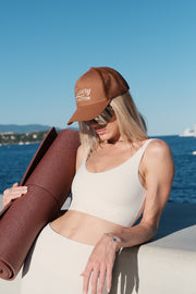 Woman holding a yoga mat against a blue wall