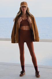 Woman wearing a brown coat and high heels on a white background
