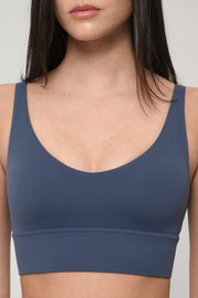 Blue sports bra worn by a woman on a plain background