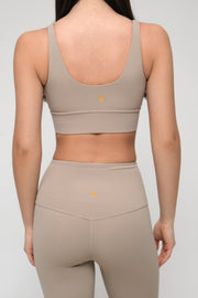 Woman wearing a beige sports bra and leggings set on a plain background