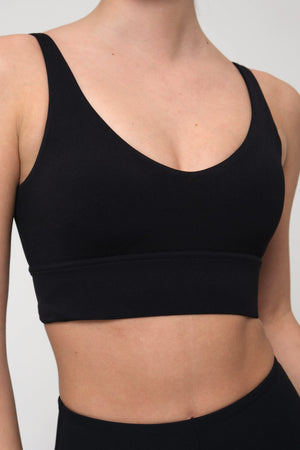 Black sports bra worn by a woman on a plain background
