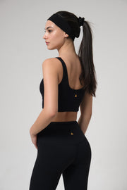 Woman wearing a black sports bra and leggings with a plain background