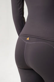 Close-up of a dark gray athletic outfit with a small golden triangle logo on a light gray background