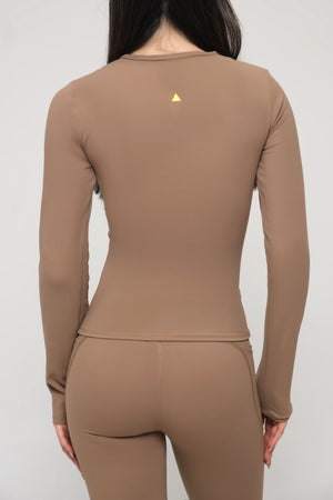 Woman wearing a brown long-sleeve top and pants with a small yellow logo on a white background