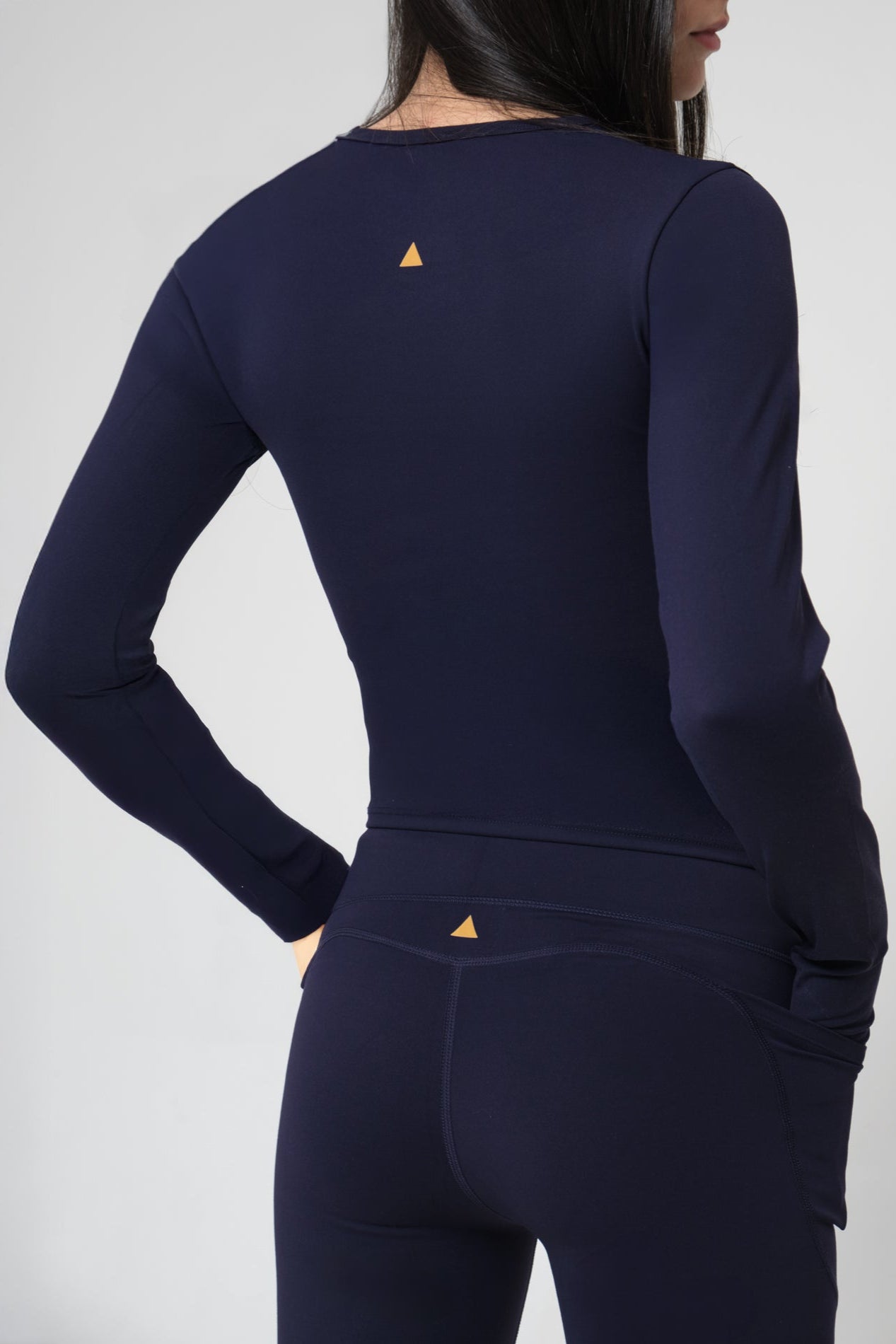Navy long-sleeve athletic top and leggings with a small logo on a plain background