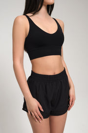 Woman wearing a black sports bra and shorts on a plain background