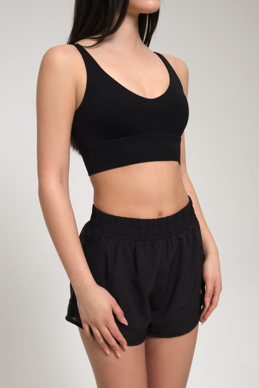 Woman wearing a black sports bra and shorts on a plain background