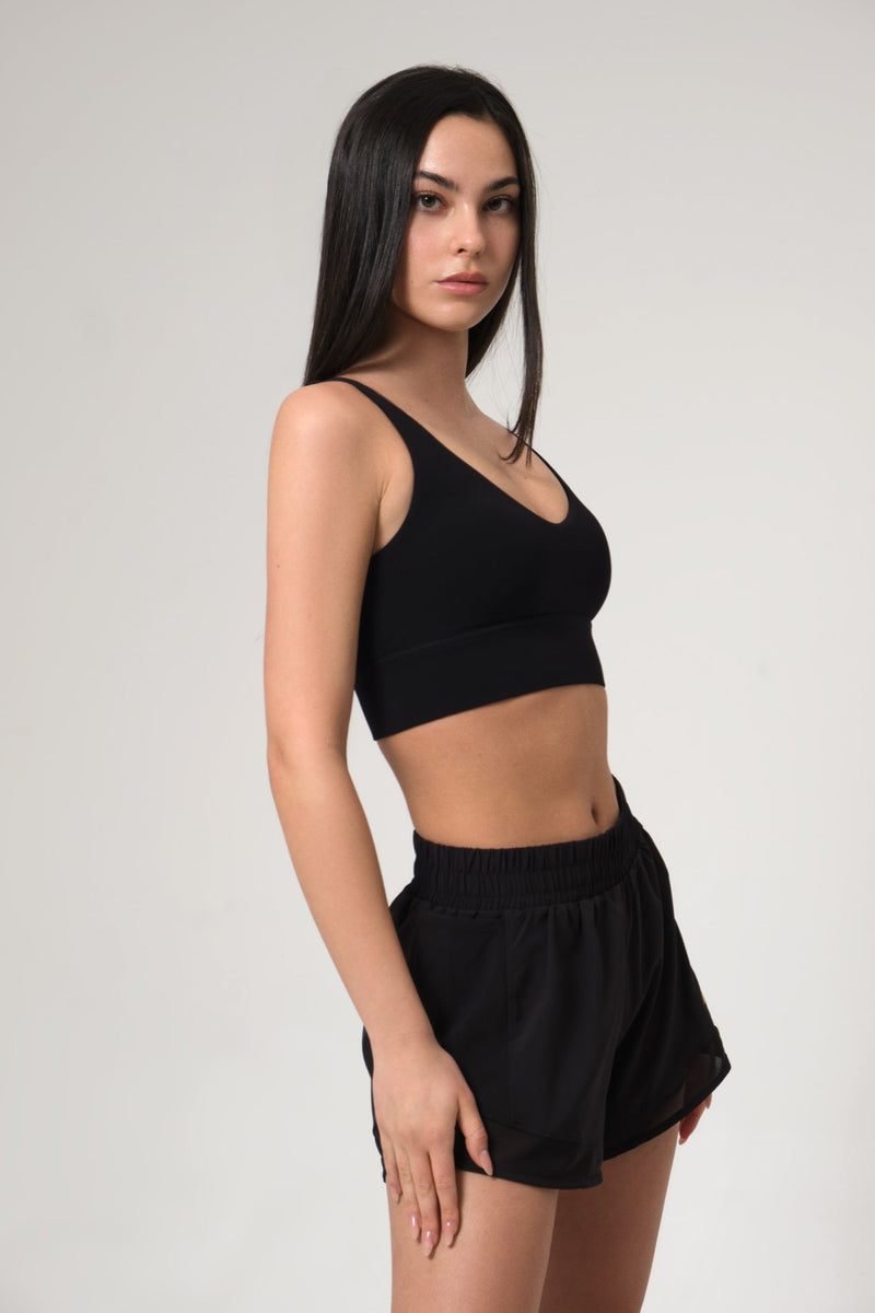 Woman wearing a black sports bra and shorts on a plain background