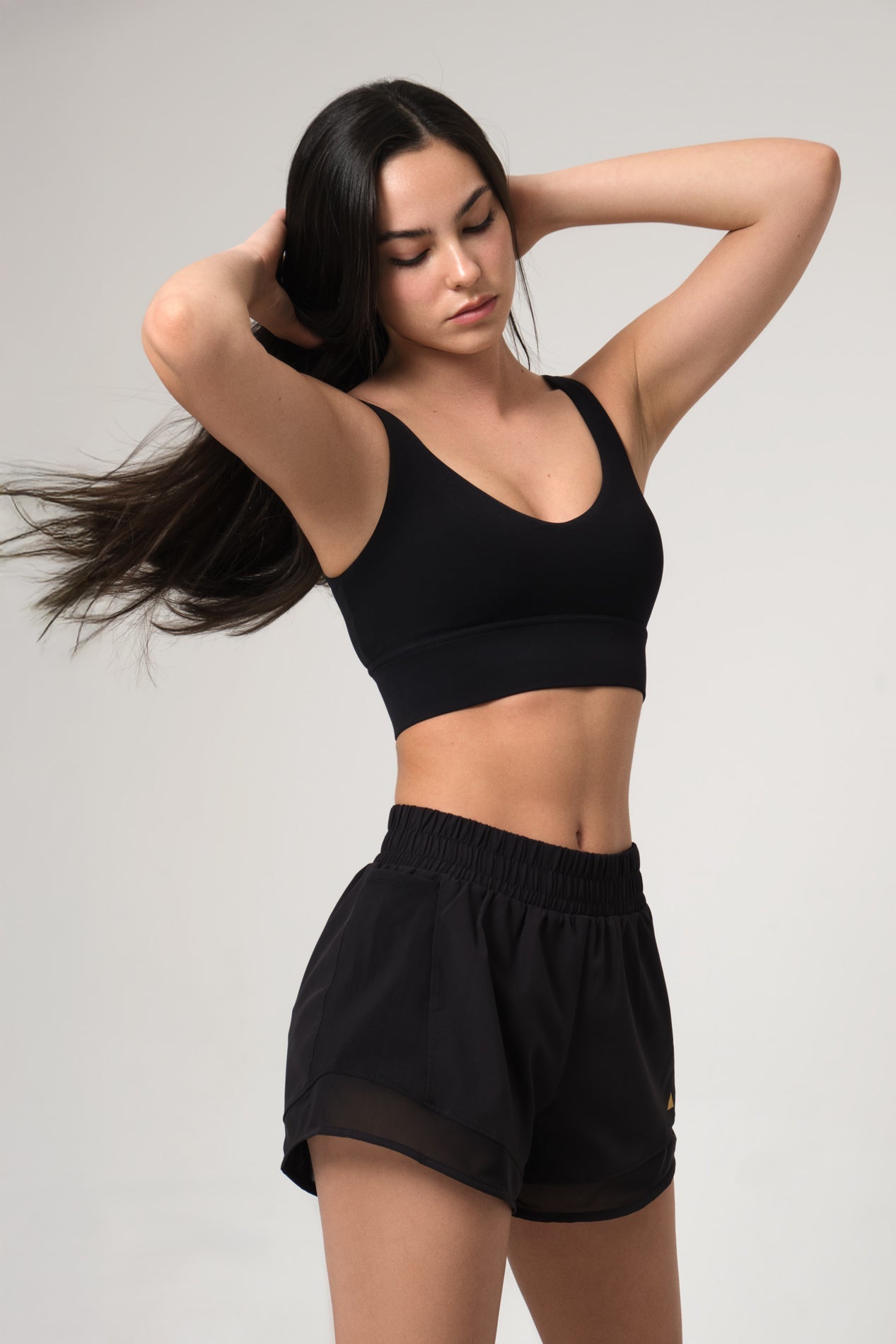 Woman wearing a black sports bra and shorts on a gray background