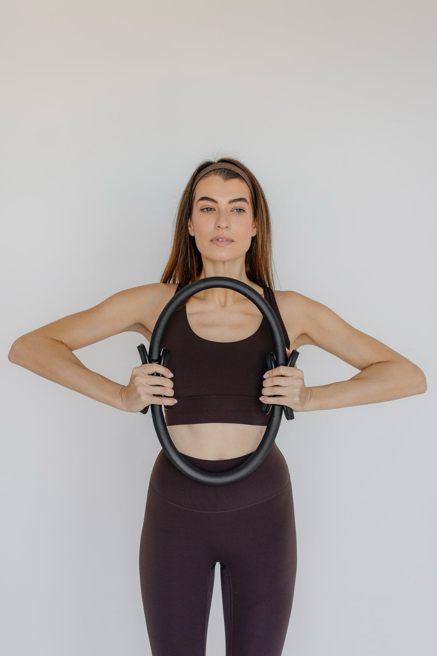 Woman holding a Pilates ring against a plain background
