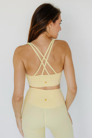 Woman wearing a yellow sports bra and leggings set on a white background