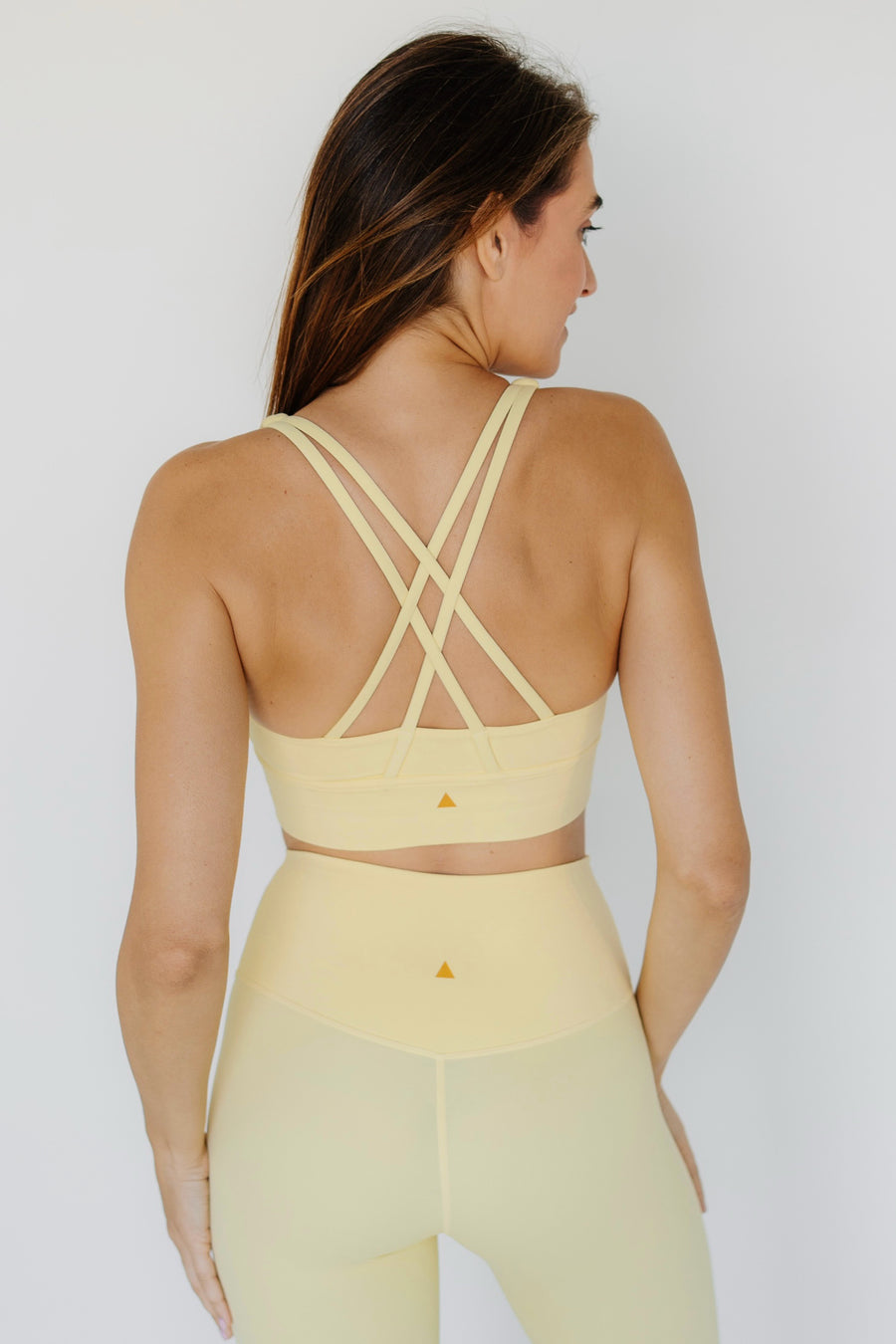 Woman wearing a yellow sports bra and leggings set on a white background