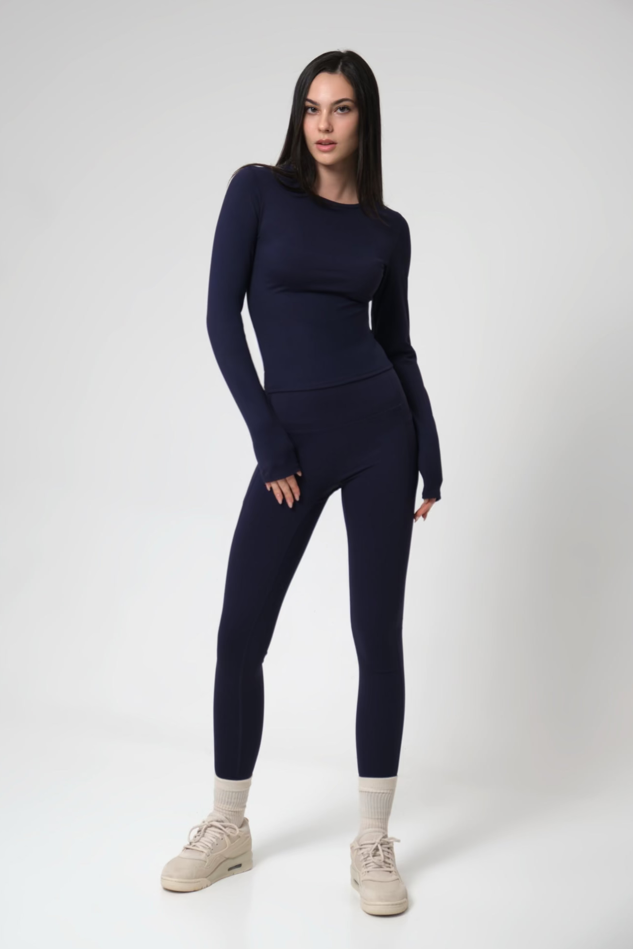 Woman wearing a navy blue athletic outfit on a white background