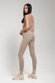 Woman wearing beige athletic outfit on a white background