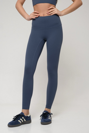 Woman wearing blue leggings and a matching top on a white background