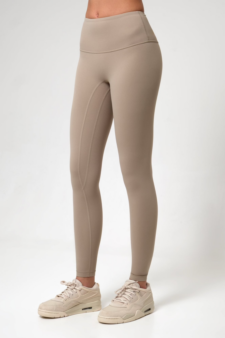 Beige leggings worn by a woman on a white background