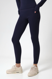 Woman wearing navy leggings and white sneakers on a white background
