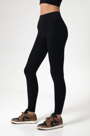 Woman wearing black leggings and brown sneakers on a white background