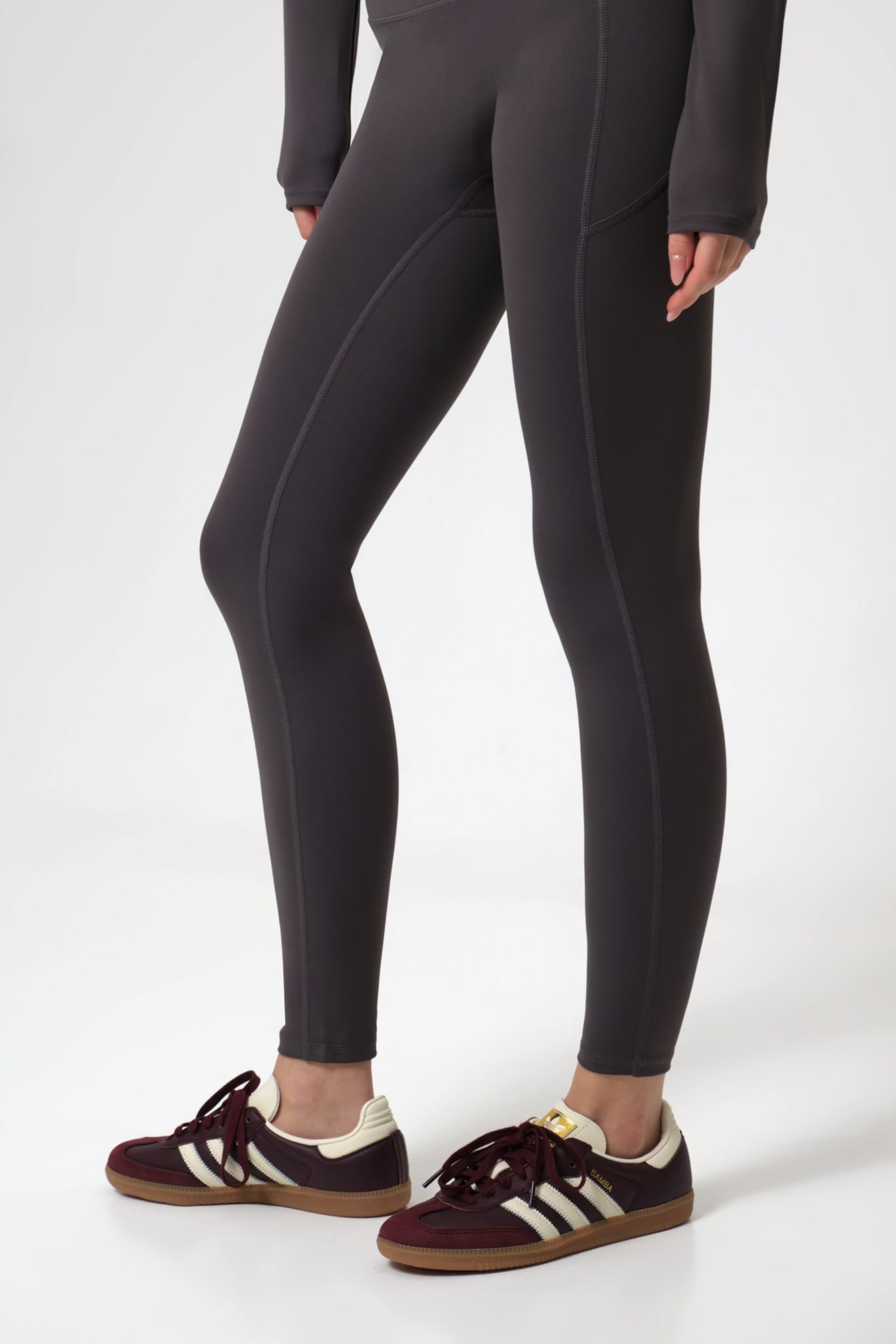 Woman wearing black leggings and brown shoes on a white background