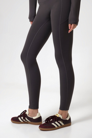 Woman wearing black leggings and brown shoes on a white background