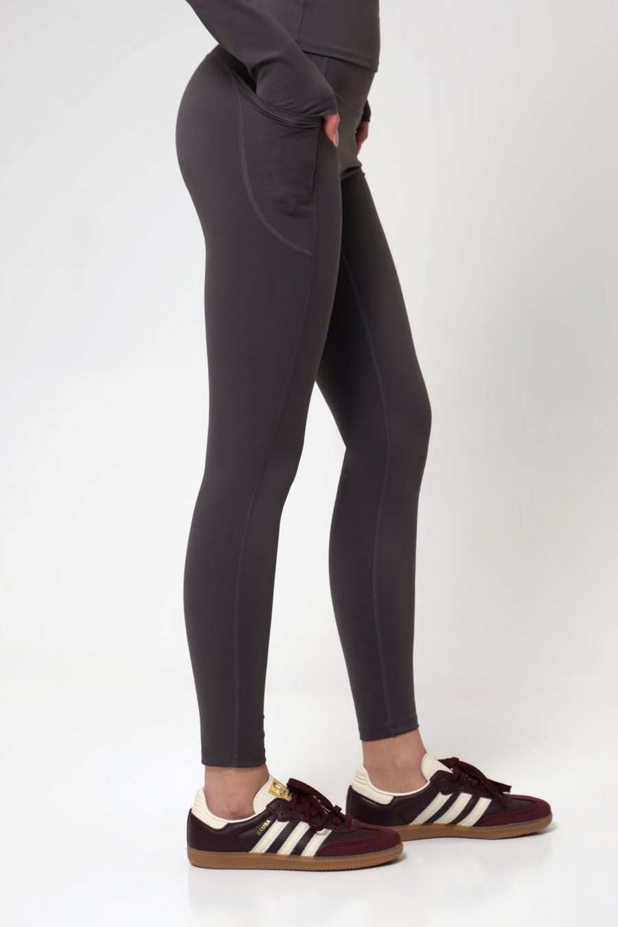 Woman wearing black leggings and burgundy sneakers on a white background