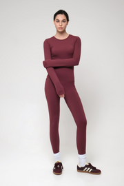 Woman wearing a burgundy outfit with Adidas shoes on a white background